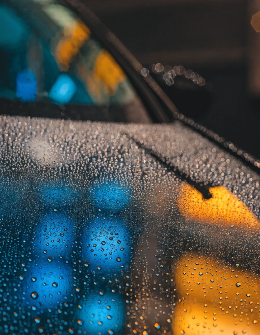 Gouttes d'eau perlant sur un pare-brise traité anti-pluie — traitement hydrophobe offert